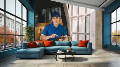 Asian delivery man in cargo van checking boxes. Wall mural