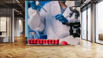 Medical or research scientist or doctor using looking at a test tube of clear solution in a lab or laboratory. Wall mural