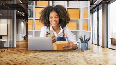 woman start up small business owner writing address on cardboard box at workplace.small business entrepreneur SME or freelance, African American female working with box at home. Wall mural