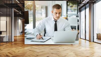 Young Asian businessman working at office with laptop and documents on table. Wall mural