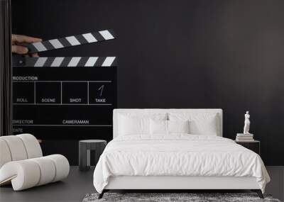 Hand is holding Black clapperboard or movie slate on black background.It have write in number. Wall mural