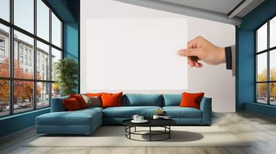 The male hand is wearing a gray suit and holding the paper board on white background. Wall mural