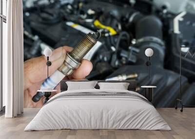 Hand of the auto mechanic holding the old spark plug on blurred engine car on background. Wall mural