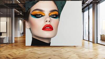 A striking beauty look featuring bold, colorful makeup with dramatic eye shadow and vibrant lipstick, complemented by a unique patterned cap. Wall mural