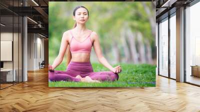 Asian model poses yoga in a park on a natural green background, health care concept, beautiful body structure, fit body Wall mural