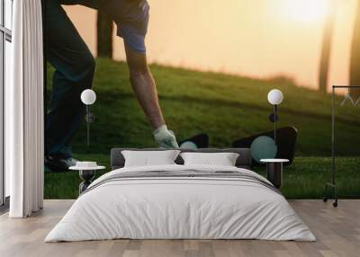 The golfer's hand grips the golf ball and tee presses down at starting point. Wall mural