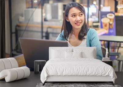 Young Asian woman using laptop computer and tablet PC to working in the modern co working space Wall mural