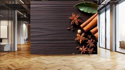 A beautiful arrangement of spices, including cinnamon sticks and star anise, complemented by a fresh orange slice on a wooden background. Wall mural