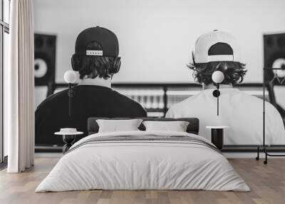 Two individuals with headphones sit in a studio, focused on music production, showcasing a collaborative environment. Wall mural