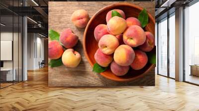 fresh ripe peaches with leaves in a bowl, top view Wall mural