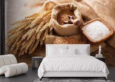 wheat ears, grains and bowl of flour on a wooden table Wall mural