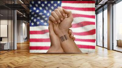 Barcode ID number on wrist of dark skinned person and national flag on background - United States Wall mural