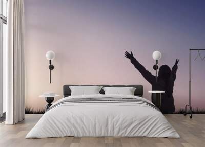 Silhouette of a girl raising arms to sky evening Wall mural