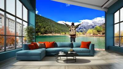 back of girl travel alone stand in front of extremely blue river ,Blue Moon valley, Jade Dragon Snow Mountain seen from a distance, Lijiang, China Wall mural