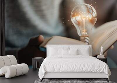 A glowing light bulb above an open book symbolizes new ideas and inspiration Wall mural