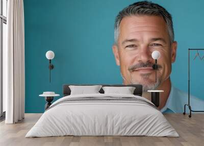 A mature man with a goatee looking directly at the camera in business casual attire against a blue background Wall mural