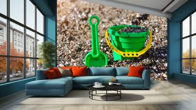 A kids spade and bucket on a pebbled shore Wall mural