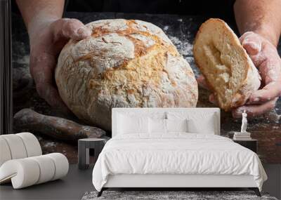 cook in a black tunic holds fresh baked bread Wall mural