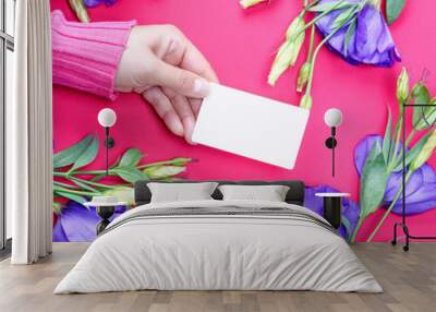 female hand in pink sweater holding a blank white paper business card Wall mural