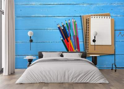 multicolored wooden pencils, blank spiral notepads on blue table Wall mural