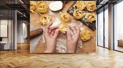 raw fettuccine pasta and two female hands are cooking pasta Wall mural