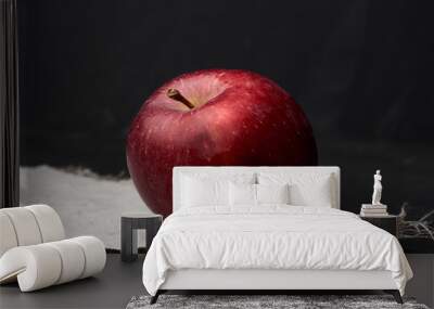 red ripe apple lies on a gray linen napkin, black background Wall mural