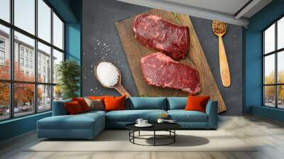 two raw pieces of classic beef steak lie on a wooden board, black table Wall mural