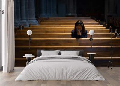 A Christian girl is sitting and praying with broken heart in the church. Wall mural