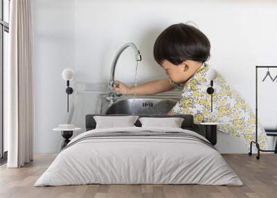 The boy is helping the mother to do the housework by washing a glass and a dish. Wall mural