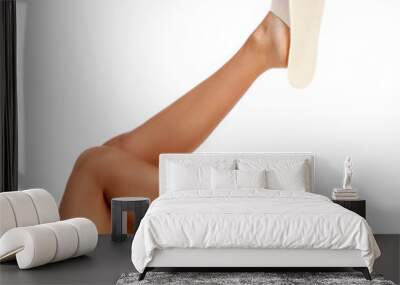 Tanned female legs in white disposable slippers, isolated on white background Wall mural