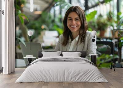 Smiling businesswoman using laptop at desk in workplace Wall mural