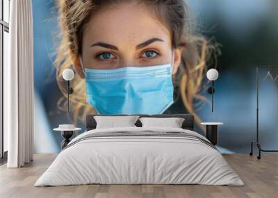 Young female nurse at camera wearing surgical mask and scrubs Wall mural