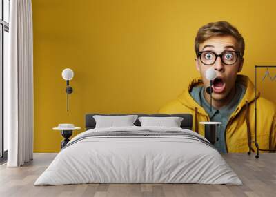 What just happened. Portrait of a shocked young man wears glasses on colour background. Wall mural