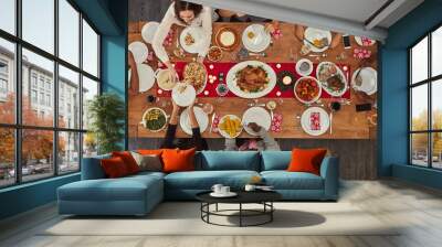 Food makes coming together easy. Shot of a group of people sitting together at a dining table ready to eat. Wall mural