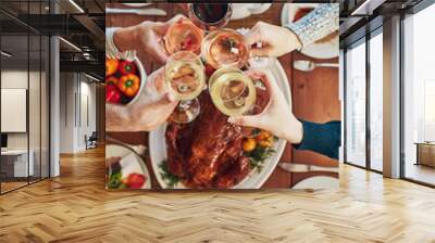 Heres to great food and great people. Hight angle shot of a group of people making a toast at a dining table. Wall mural