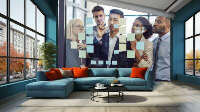 Making everyone part of the process of success. Shot of a group of young businesspeople having a brainstorming session together in a modern office. Wall mural