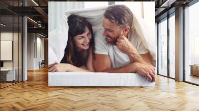 So nice of you to join me. Shot of a cheerful young couple crawling out of bed while having a laugh together during morning hours. Wall mural