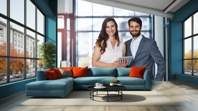 We run our company on teamwork and modern technology. Portrait of a young businessman and businesswoman using a digital tablet together in an office. Wall mural