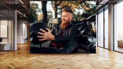 Biker sitting on the ground against his chopper Wall mural