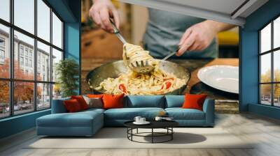 Chef cooking pasta, pan on wooden kitchen table Wall mural