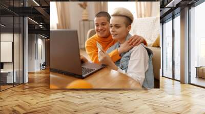 Happy lgbt woman doing online payment using laptop and credit card Wall mural