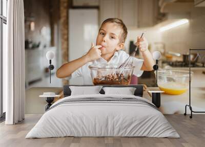 Male kid tastes melted chocolate in a bowl Wall mural