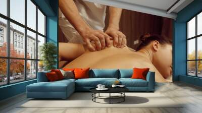 Male masseur rubbing hands to slim woman Wall mural