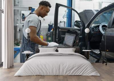 Male mechanic using laptop, car service Wall mural