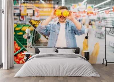 Male person funs with yellow peppers in market Wall mural