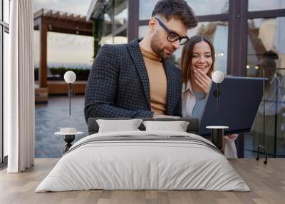 Man and woman using laptop standing together on roof terrace Wall mural