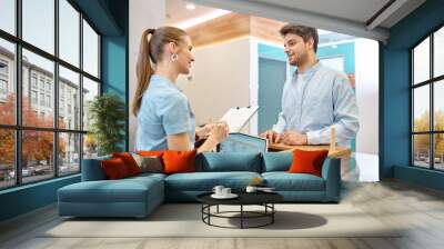 Man talking to professional receptionist in clinic Wall mural