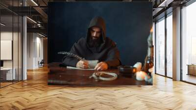 Medieval monk sitting at table and write, top view Wall mural