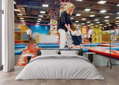 Mother and little girl jumping on a trampoline Wall mural