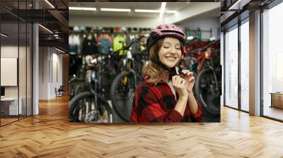 Portrait of happy smiling woman cyclist wearing safety helmet at sport shop Wall mural